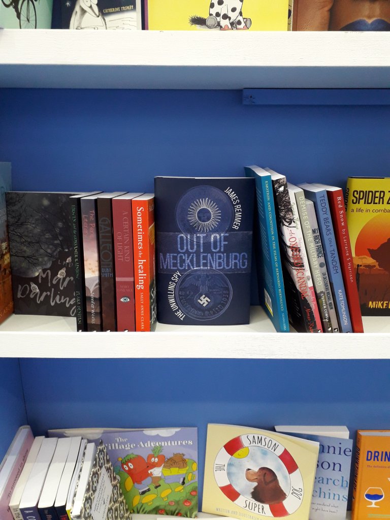 Bookshelf displaying a range of Matador books, with the blue-covered spy novel Out of Mecklenburg in the middle of the image.